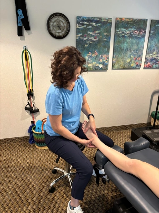 Dr. Fawn Ray treating a female patient's extremity pain with hands-on chiropractic therapy